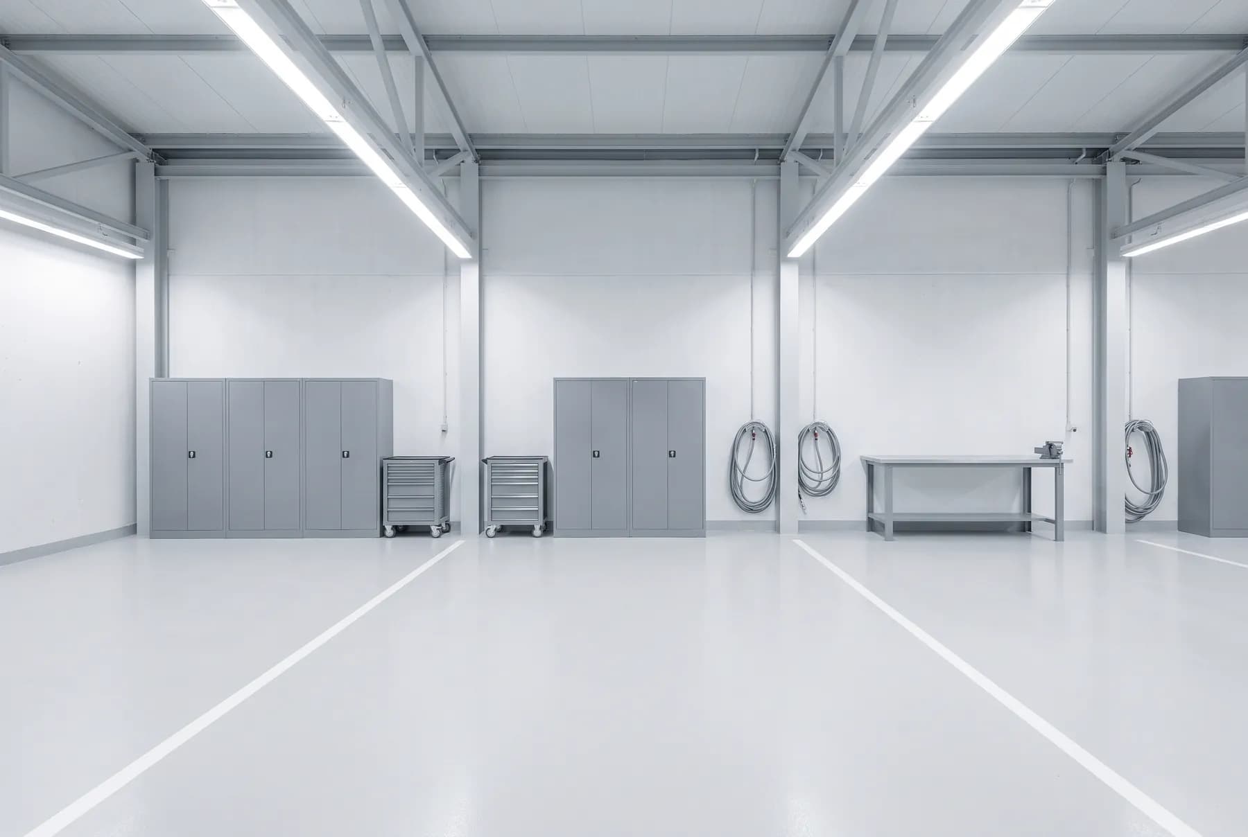 Werkstatthalle mit Werkzeugschränken, Werkbank und hellem Betonboden — Symbolbild
